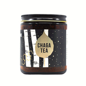 Amber glass jar of wild foraged Chaga tea with a black label featuring birch tree and gold leaf designs.