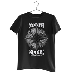 Black short-sleeve t-shirt on a hanger with a white distressed compass rose graphic and text reading NORTH SPORE PORTLAND-MAINE.