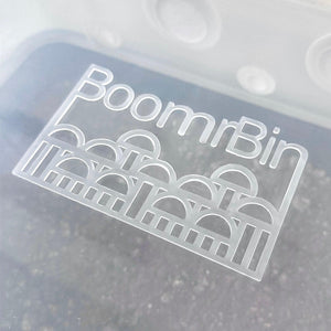 Clear plastic Boomr Bin mushroom monotub with a white logo featuring arch patterns for indoor cultivation.