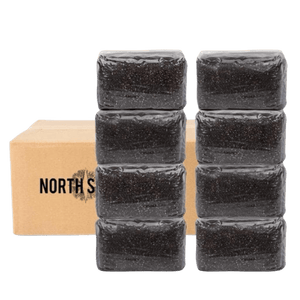 Two vertical stacks of four dark, speckled blocks in plastic wrap in front of a cardboard box.