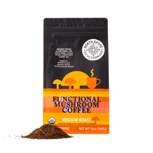 Black pouch of Functional Mushroom Coffee with yellow, orange, and pink graphics, plus a small pile of ground coffee.