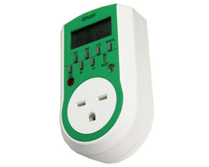 Green and white digital plug-in timer with LCD screen, control buttons, and UK-style three-pin outlet.