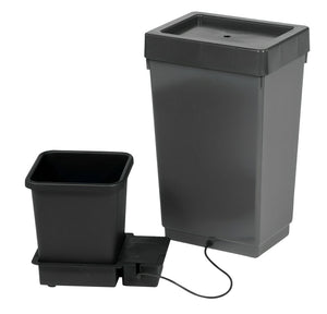 A black square planting pot attached to a large grey reservoir tank by a small black hose against a white background.