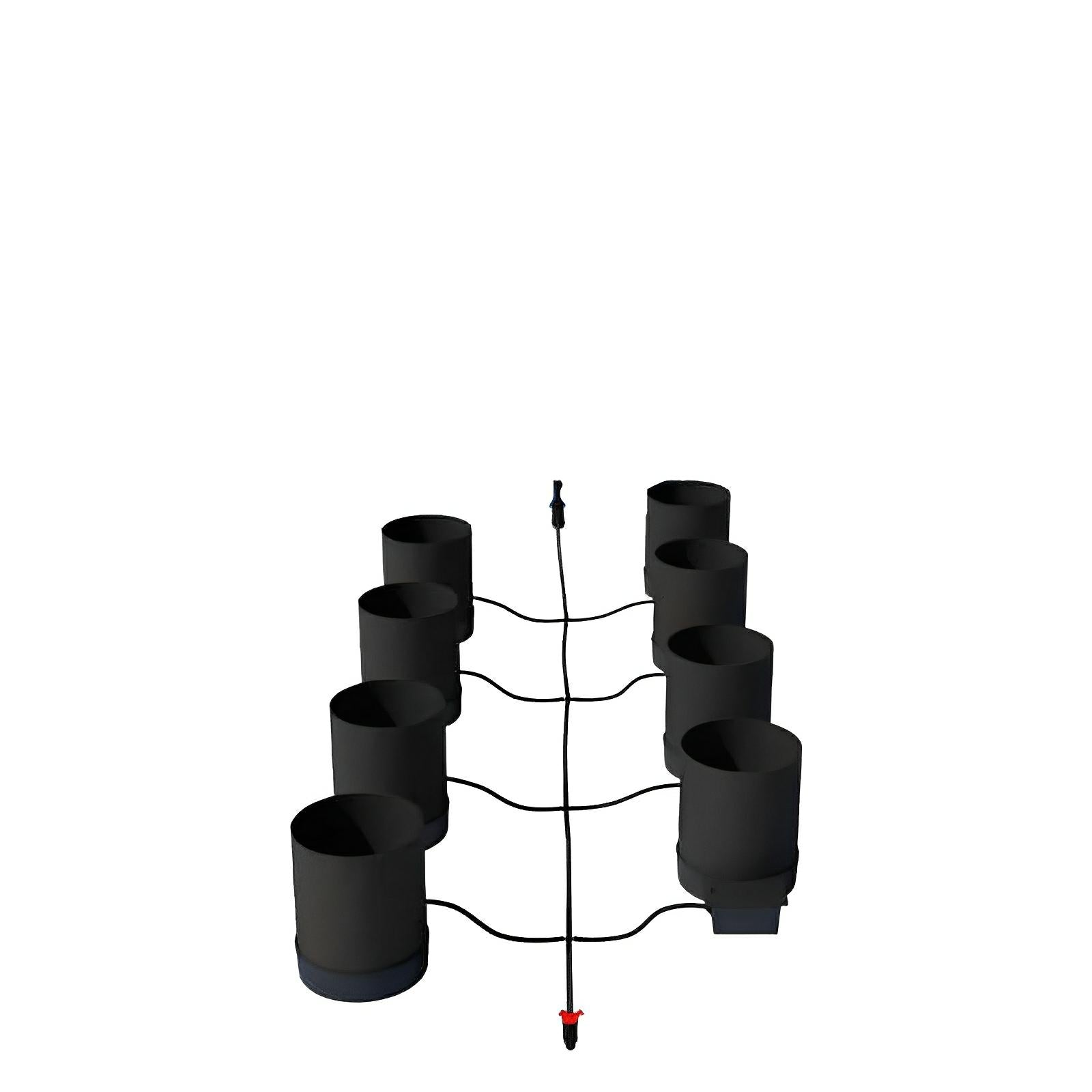 High-angle view of eight black cylindrical hydroponic buckets connected by a central irrigation line.