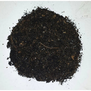 Top-down view of dark, coarse, organic potting soil spread in a circular pile against a white background.