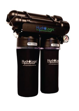 Hydrologic water filter system with two black housings, pressure gauge, and labeled pre-carbon and sediment filters.
