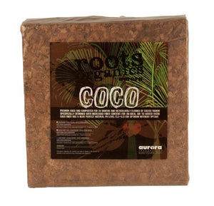 A square, compressed brick of Roots Organics coco fiber coir wrapped in clear plastic with a branded label.