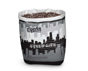 Open bag of Roots Organics potting soil showing dark, textured mix with white perlite bits. Grey cityscape design.