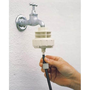 Hand attaches black tubing to a beige faucet adapter installed on a silver outdoor wall spigot.